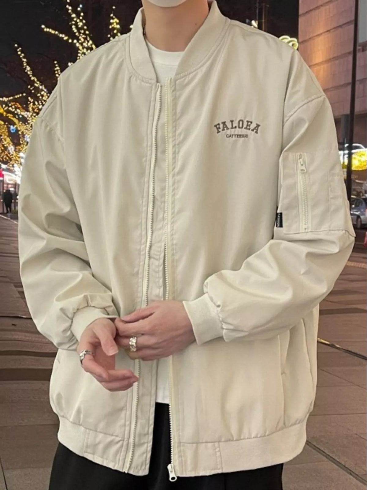 Apricot bomber jacket with zip front, chest logo and zippered sleeve pocket.