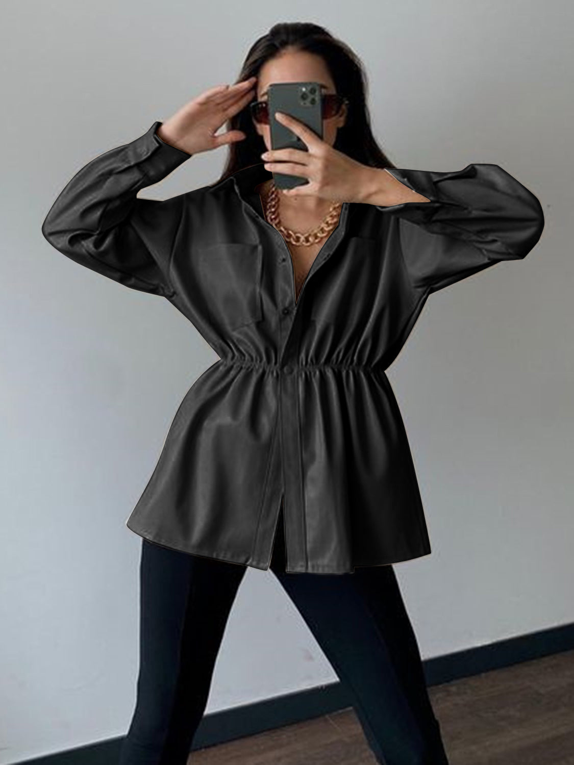 Black faux leather shirt jacket with gathered waist and button front.