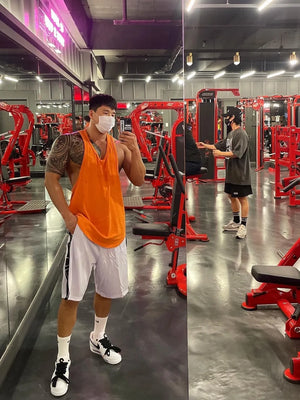 Orange scoop neck workout tank top with white athletic shorts.