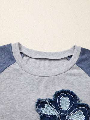 Grey raglan shirt with blue denim embroidered flower patch detail and crew neck.