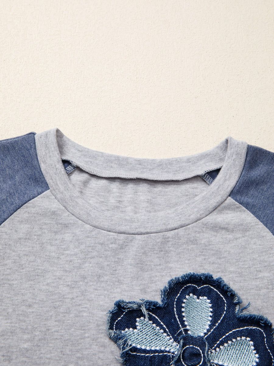 Grey raglan shirt with blue denim embroidered flower patch detail and crew neck.