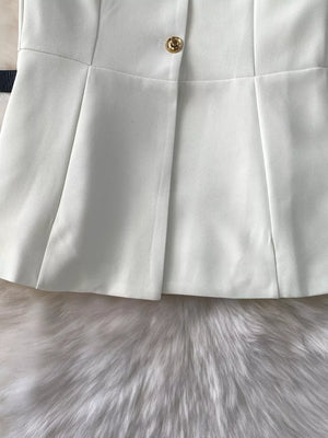 White belted two-piece set with gold button detail and pleated skirt.