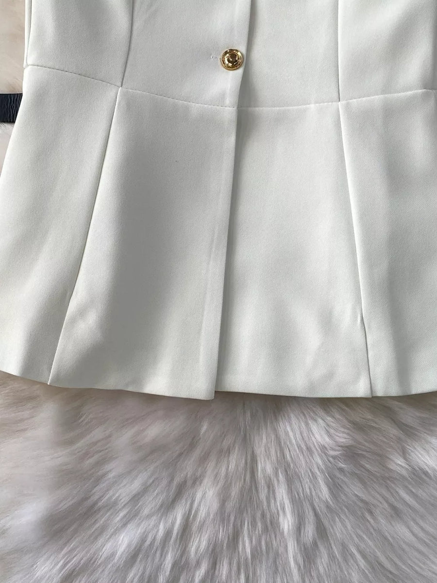 White belted two-piece set with gold button detail and pleated skirt.