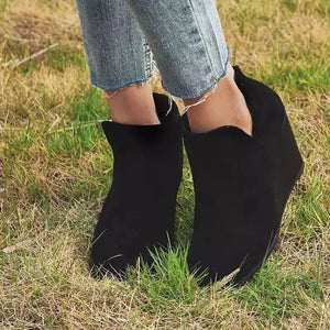 Black wedge ankle boots with a scalloped topline, styled with cropped jeans.