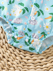 Baby bodysuit with bunny, carrot, and flower print on blue fabric, featuring white buttons.