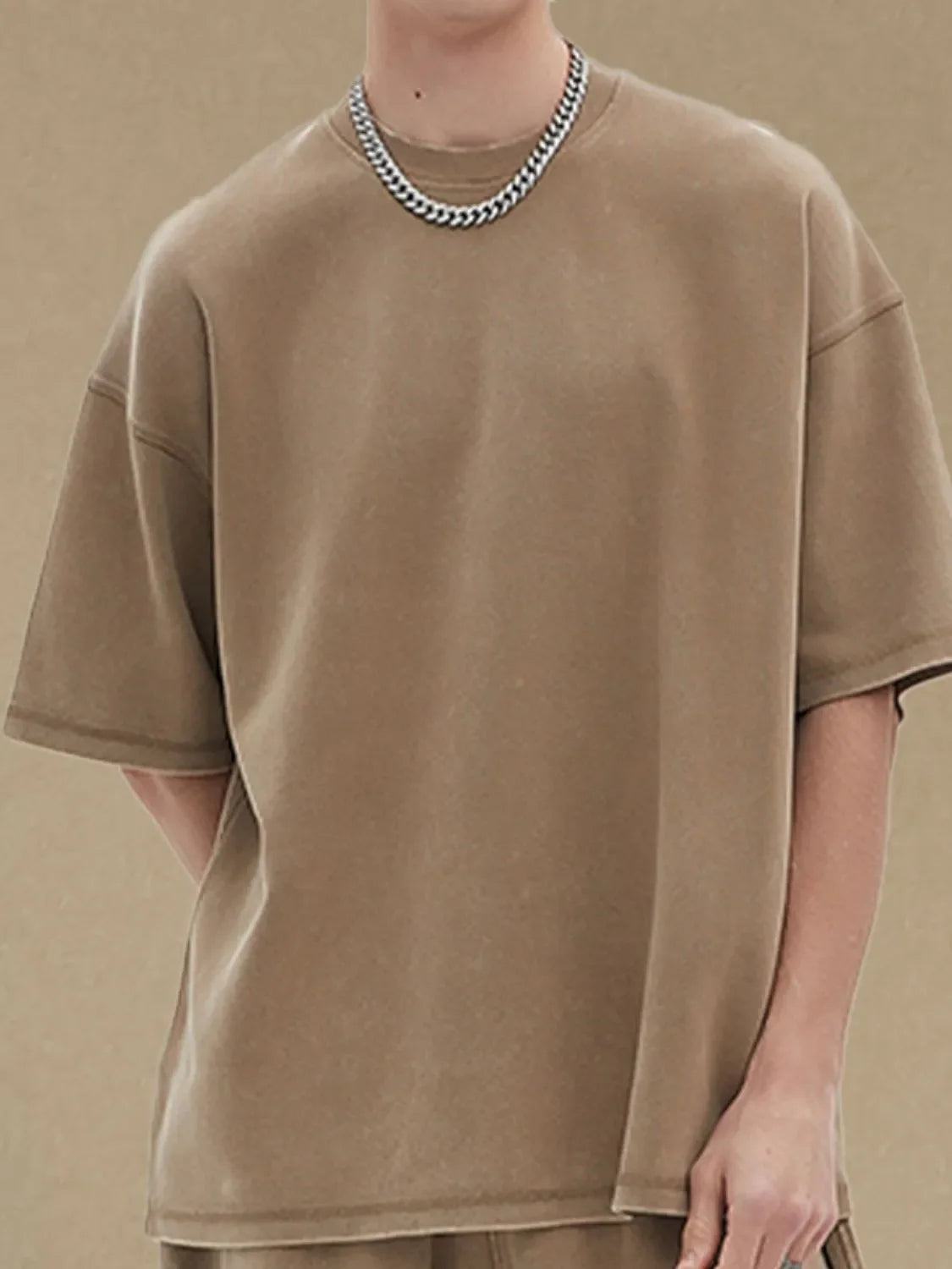Khaki half sleeve tee with crewneck and relaxed fit, styled with a chain necklace.