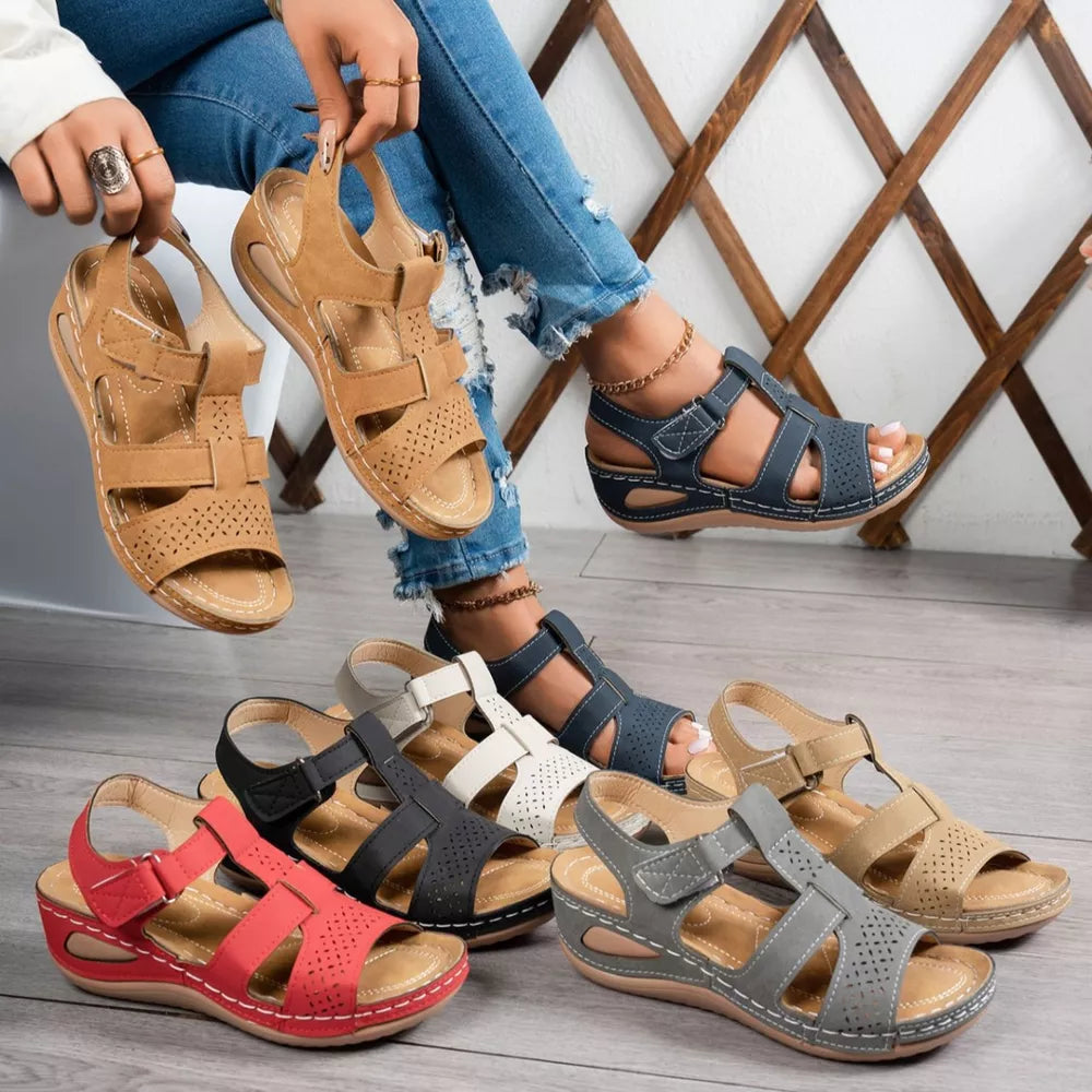 Elegant perforated mid-wedge sandals in black, blue, brown, gray, red, and gray/white with adjustable straps.