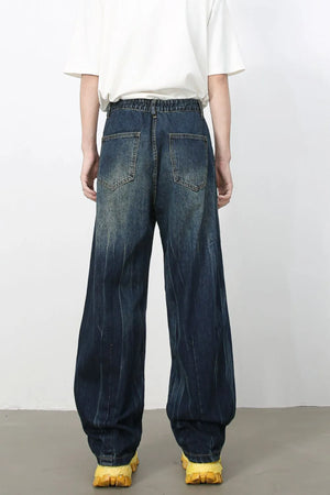 Dark wash pleated wide-leg denim trousers with distressed vertical stripes and elastic waistband.