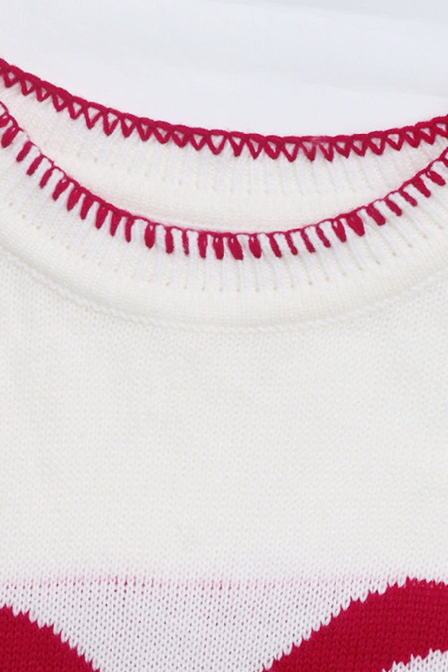 White knit sweater with red zigzag trim detail and festive bow graphic.