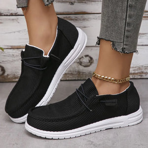 Textured slip-on espadrille sneakers in black with white soles and decorative laces.
