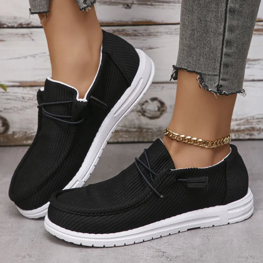 Textured slip-on espadrille sneakers in black with white soles and decorative laces.