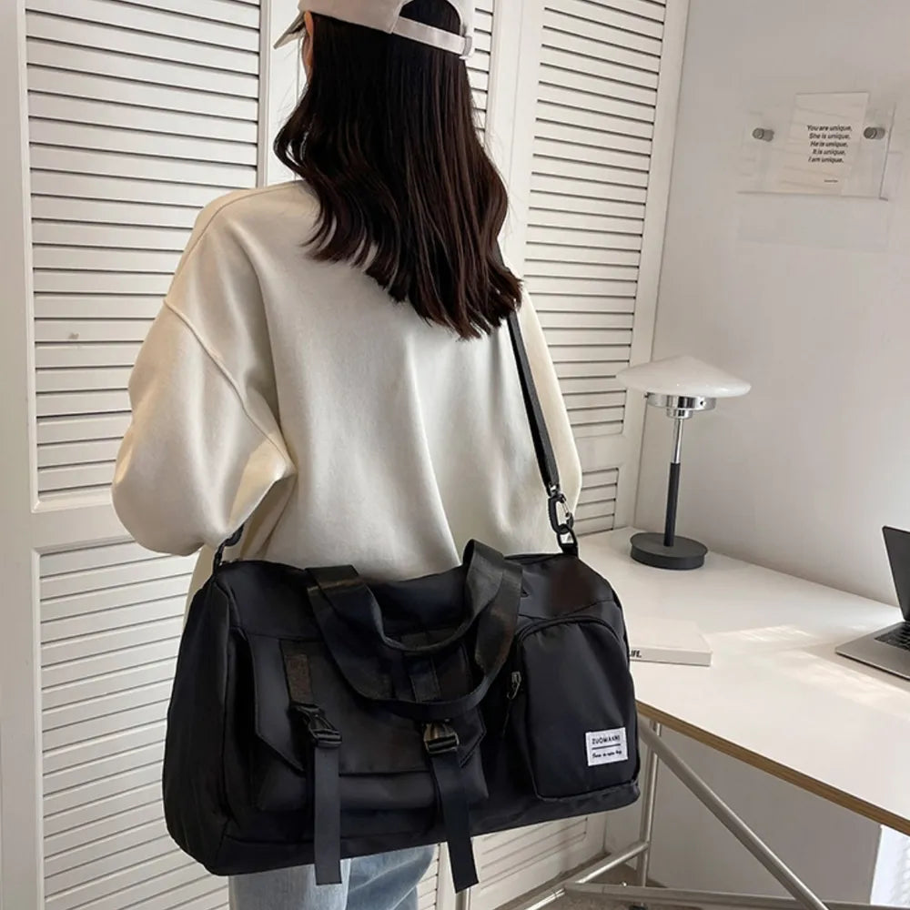 Black utility traveler holdall duffel bag with buckle details and multiple pockets.