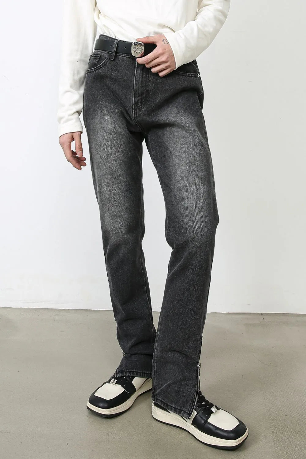 Dark washed denim trousers with split hem detail and zipper closure.