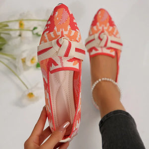 Knitted pointed flats in a coral and white pattern with a cream bow detail.