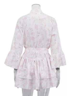 White dress with pink floral and butterfly print, belted waist, tiered ruffled skirt, and bell sleeves.