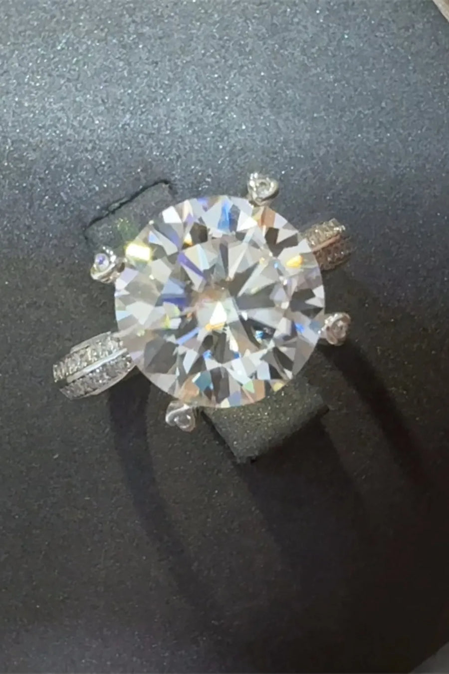 Silver pavé band round moissanite engagement ring with a large center stone.