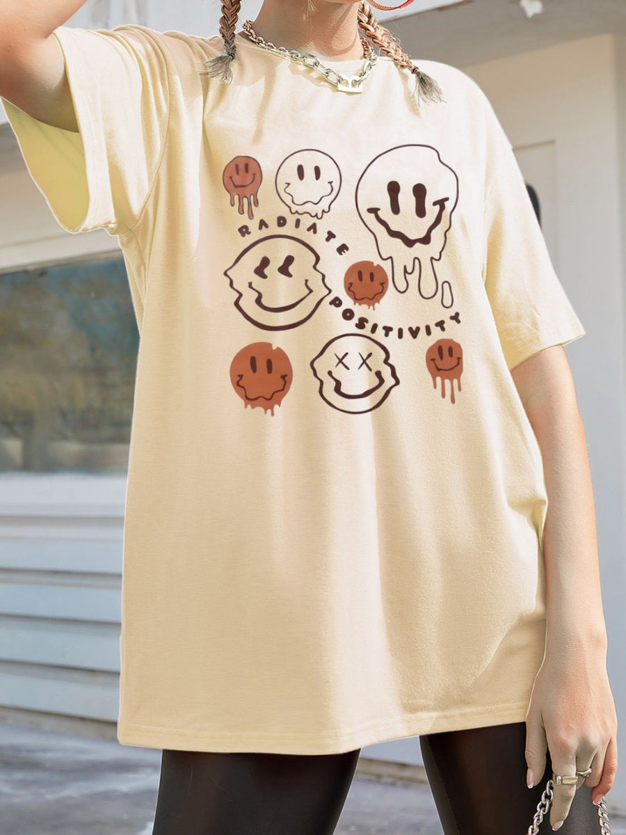 Tan oversized graphic tee with melting smiley faces and "Radiate Positivity" text.
