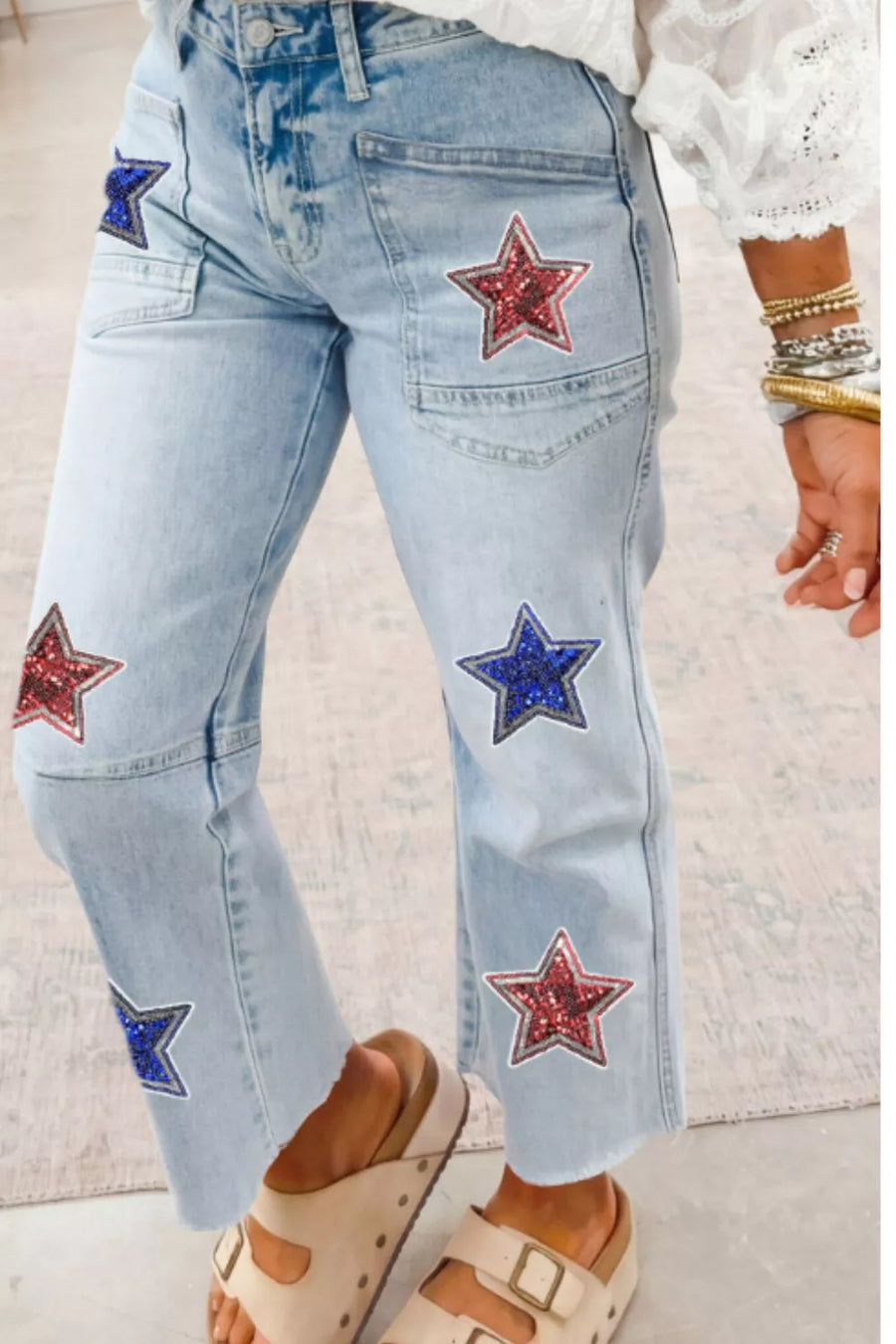 Light wash denim cropped jeans with red and blue sequin star patches and utility pockets.