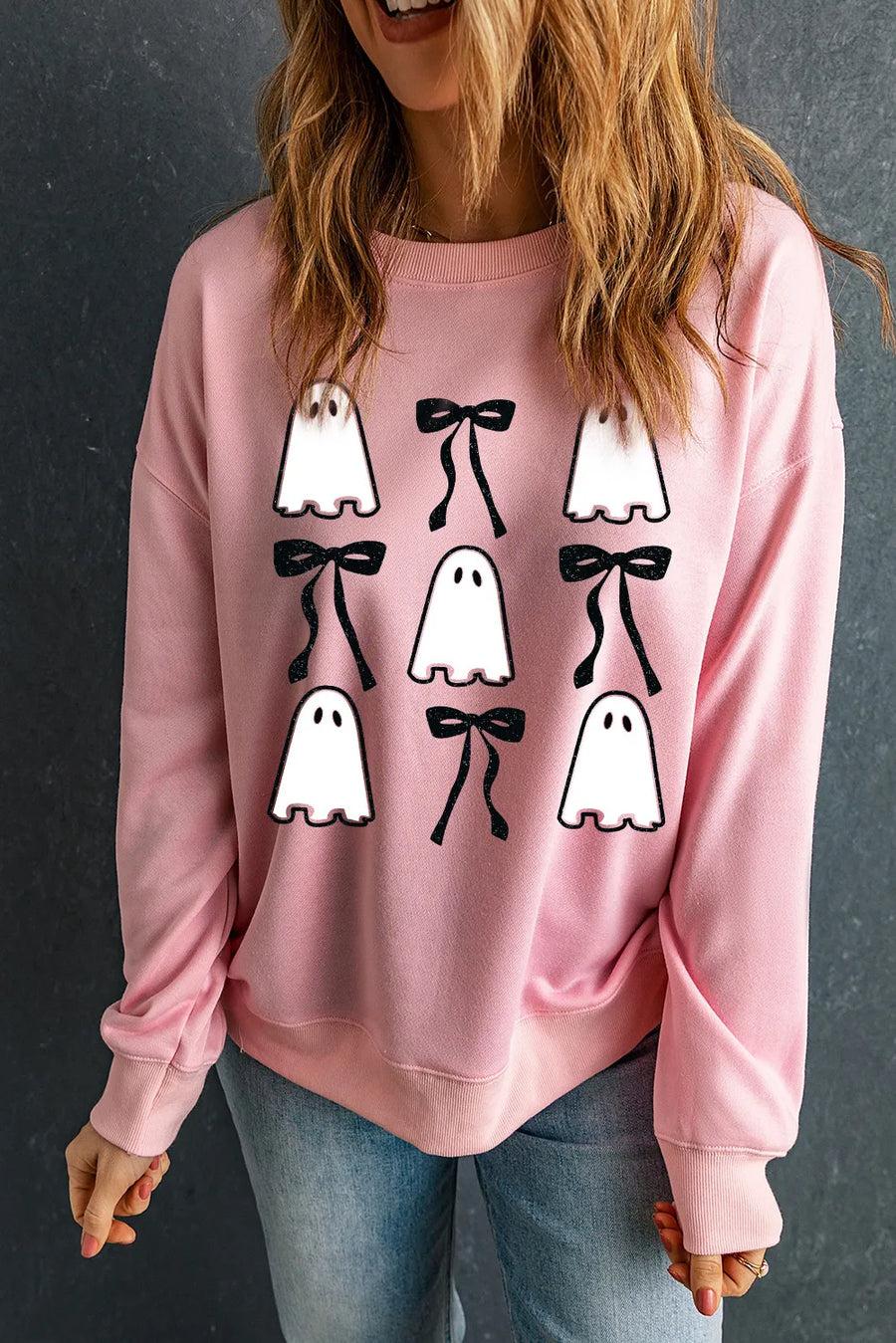 Blush pink crewneck sweatshirt with a ghost and bow graphic pattern.