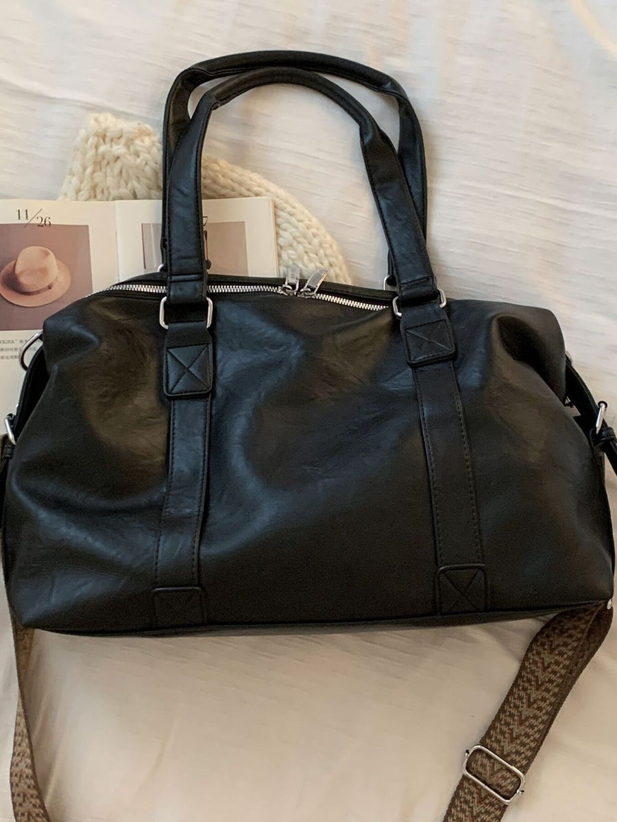 Black pu leather shoulder bag with silver hardware and a patterned strap