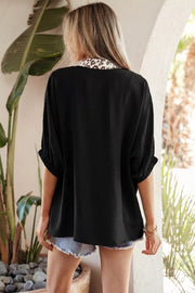 Black polyester tunic with leopard print notched neckline and cuffed sleeves.