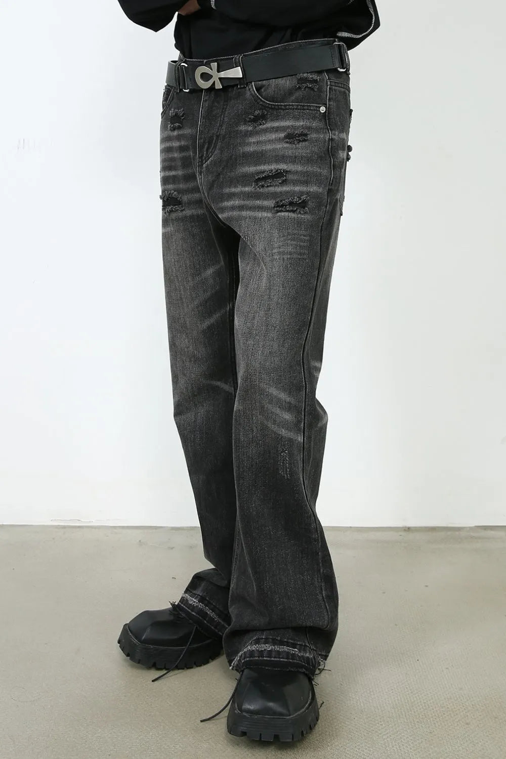 Distressed flare jeans in washed black denim with a bootcut leg and frayed hem detail.