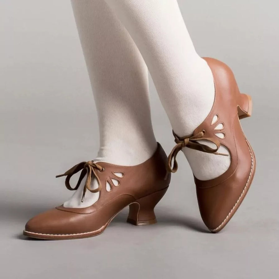 Brown leather mary jane heels with cutouts and lace-up ties, worn with white socks.