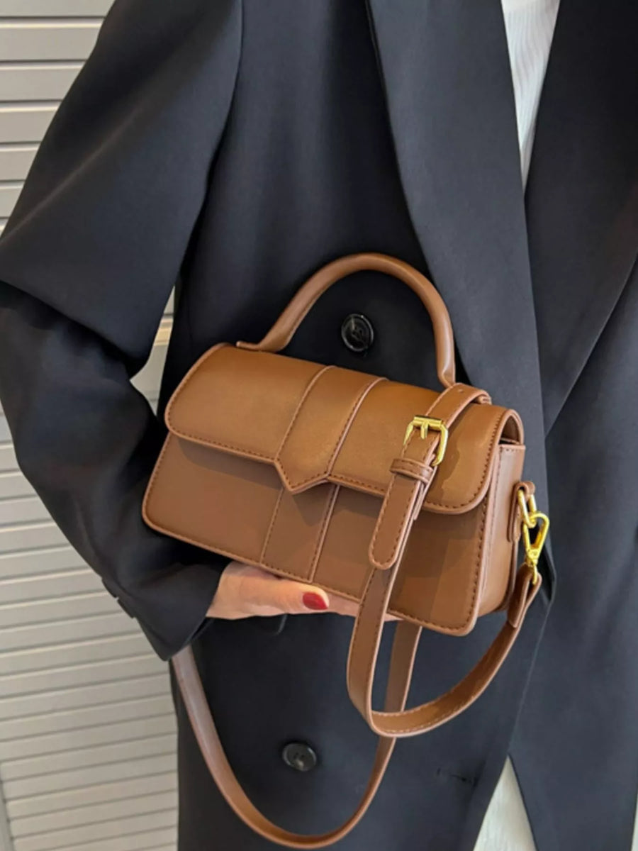 Brown top handle shoulder bag with gold buckle detail and adjustable strap.
