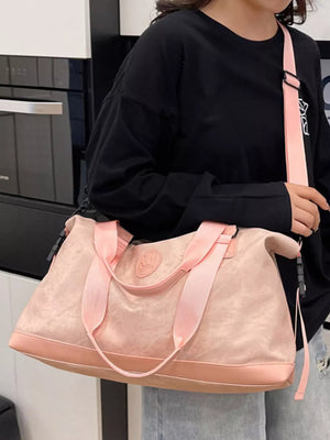 Pink Oxford cloth duffel bag with pink straps and brown trim, worn crossbody.