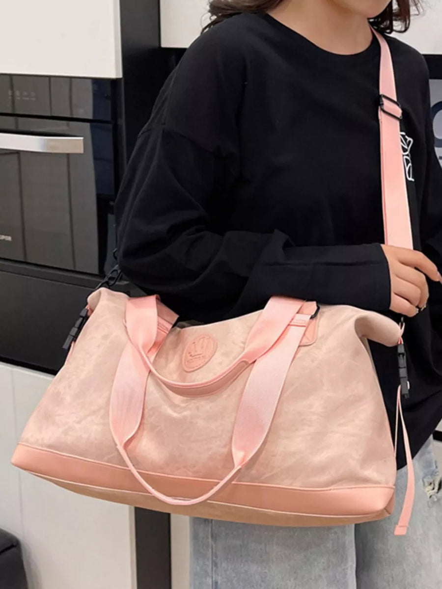 Pink Oxford cloth duffel bag with pink straps and brown trim, worn crossbody.