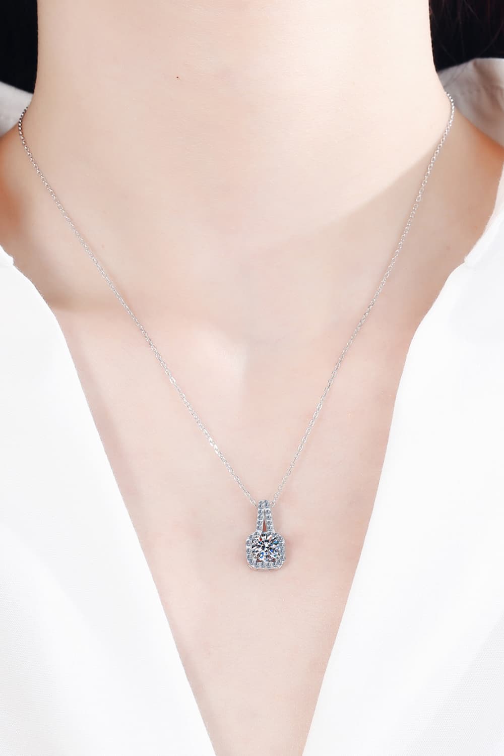 Silver moissanite pendant necklace with cushion halo setting on a delicate chain.
