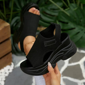 Black open-toe wedge sandals with chunky sole and knit upper.