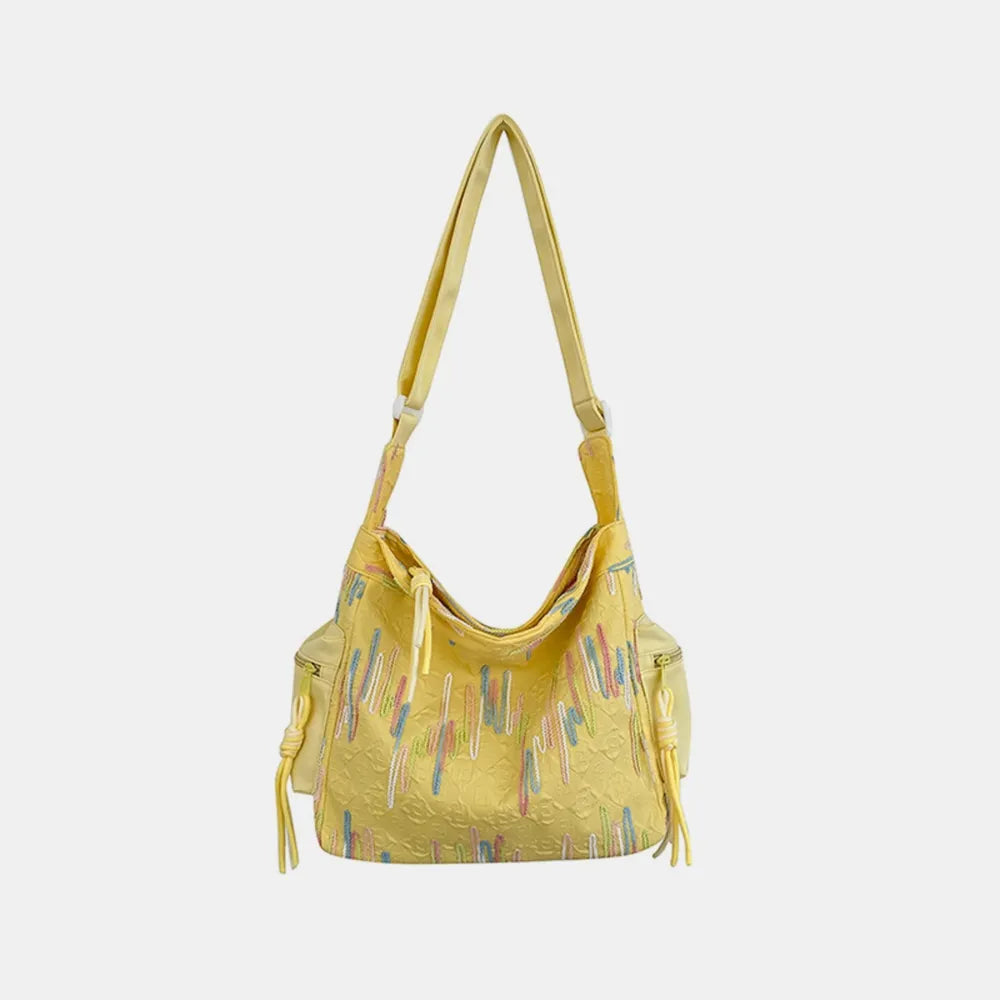 Light Yellow slouchy shoulder bag with embroidered colorful vertical lines and tassel details.