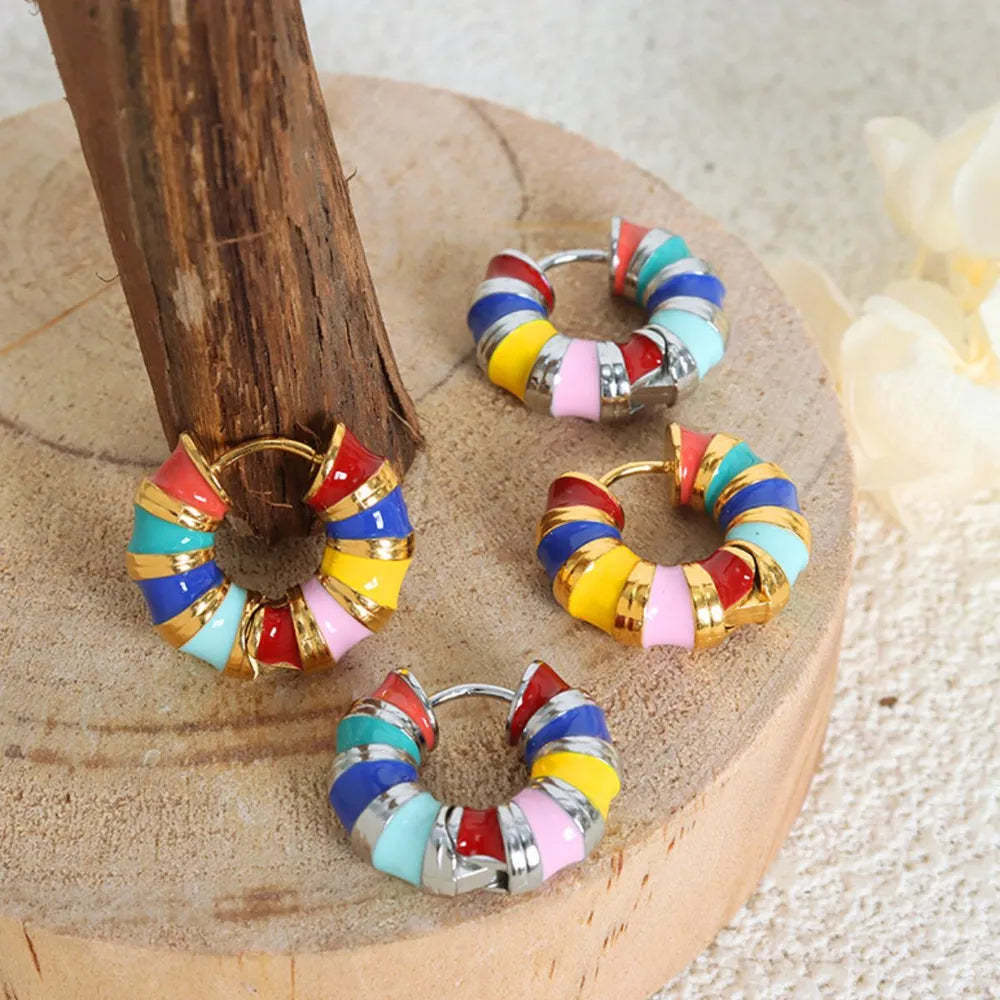 Rainbow enamel segmented hoop earrings with gold accents and silver posts.