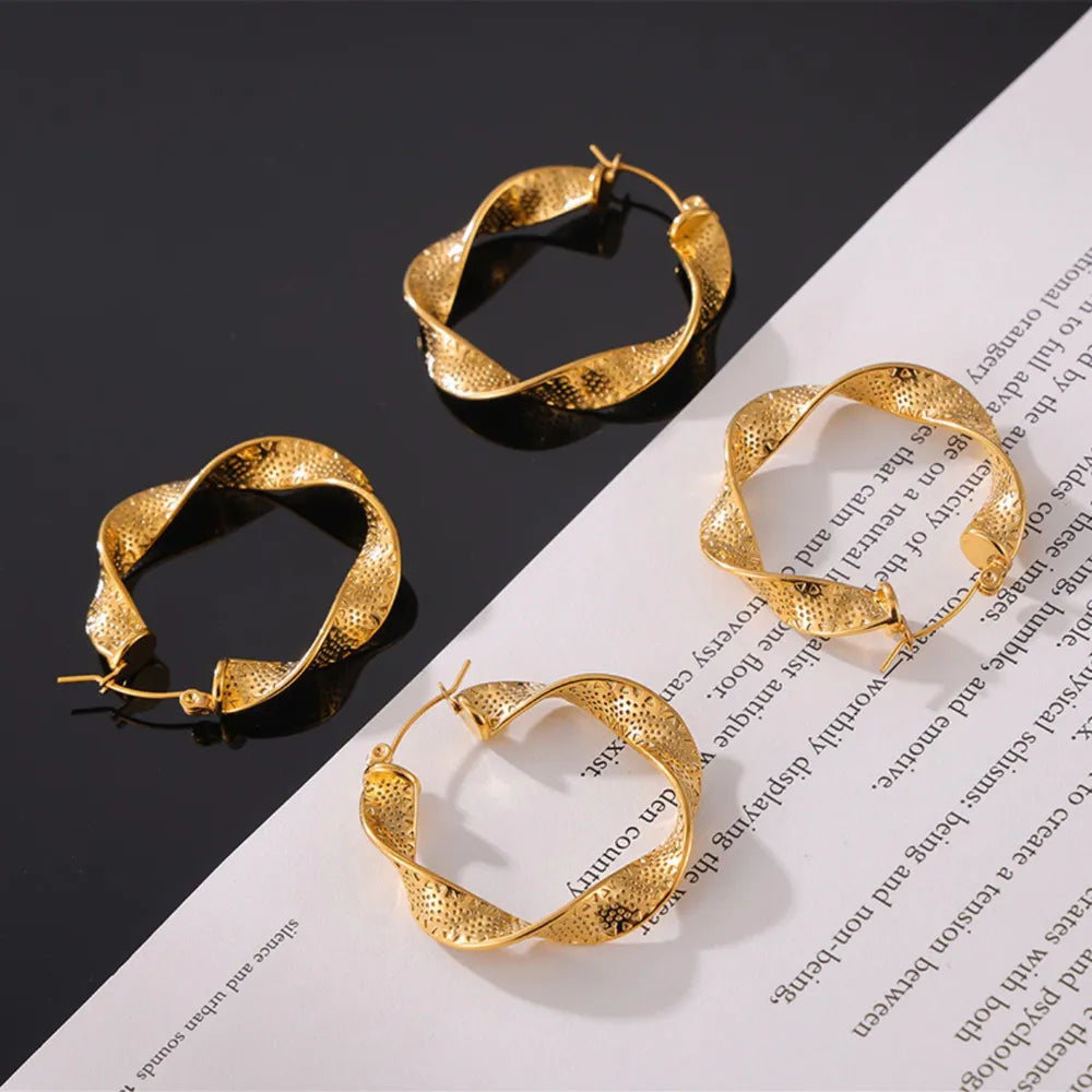Gold textured spiral hoop earrings with a twisted design and subtle dot pattern.