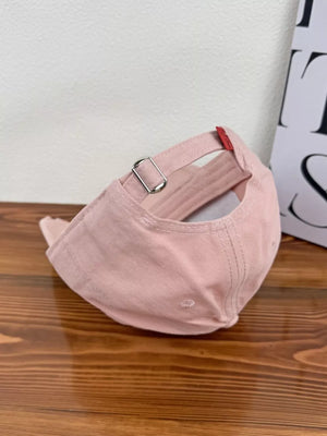 Pink baseball cap with adjustable strap and red tab detail