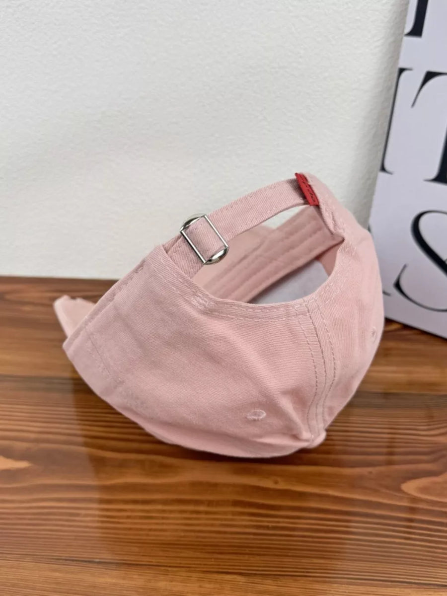 Pink baseball cap with adjustable strap and red tab detail