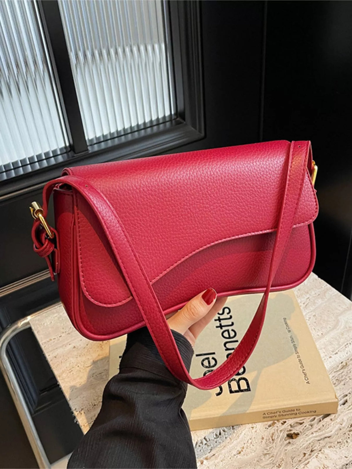 Red faux leather crossbody bag with a curved flap and gold hardware.