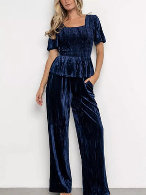 Navy blue velvet two-piece set with smocked bodice, peplum hem, and wide-leg pants.