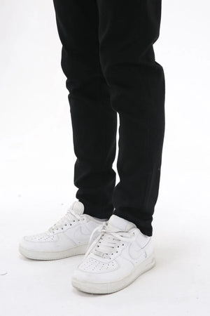 Black slim-fit stretch denim trousers with white sneakers