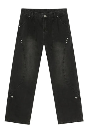 Dark wash denim jeans with asymmetric seams and silver stud details.