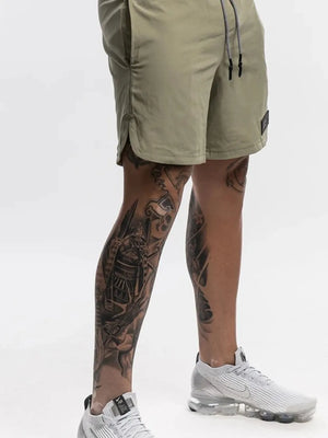 Khaki performance shorts with drawstring and logo patch, showing side slit detail.