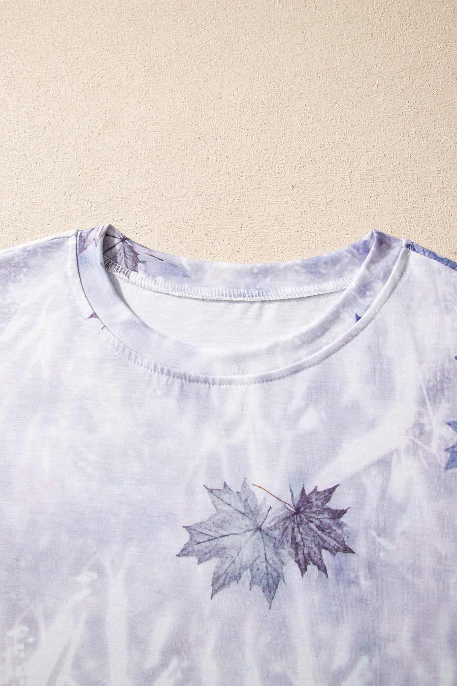 Crew neck t-shirt with a faded purple and white tie-dye pattern and a leaf print.