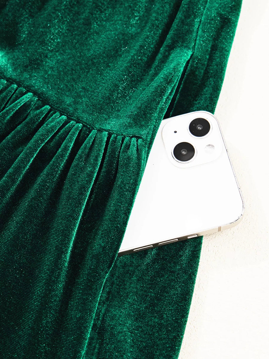 Dark green velvet mini dress with tiered skirt and hidden pocket holding a smartphone.