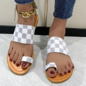 Checkered toe-loop flat sandals with white and grey pattern and orange sole.
