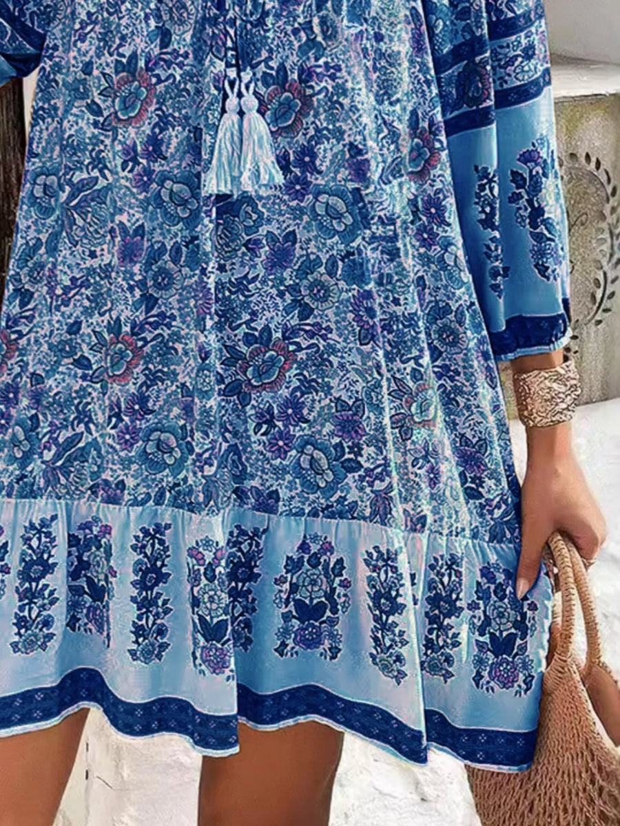 Light blue floral mini dress with tassel tie neckline and tiered hem.
