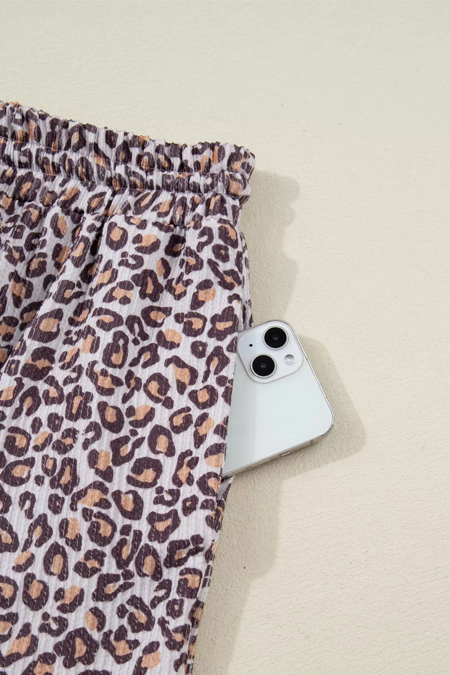 Leopard print ribbed loungewear pants with elastic drawstring waist and side pocket holding a phone.