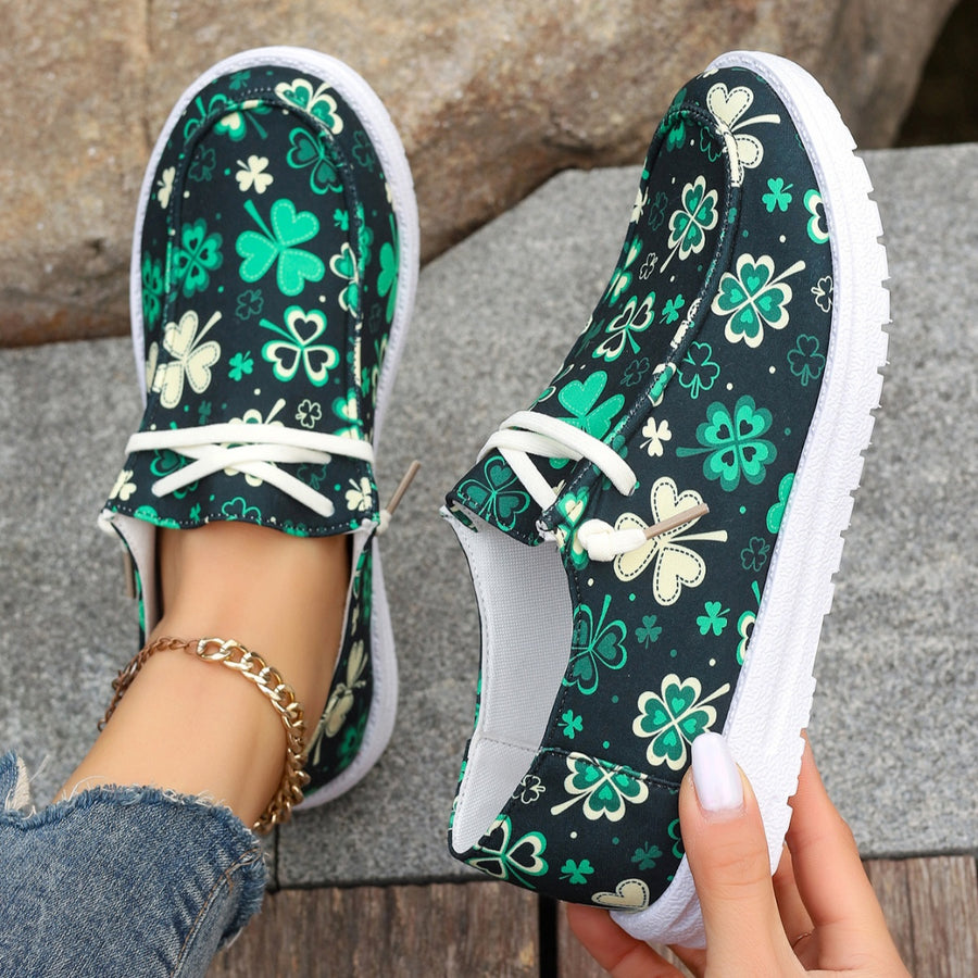 Clover print canvas slip-on sneakers with decorative white laces and white soles.