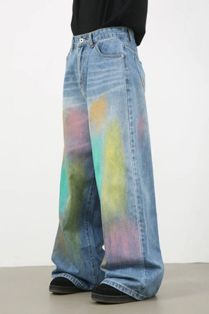 Graffiti wash wide leg denim trousers in medium blue with colorful paint splatters.