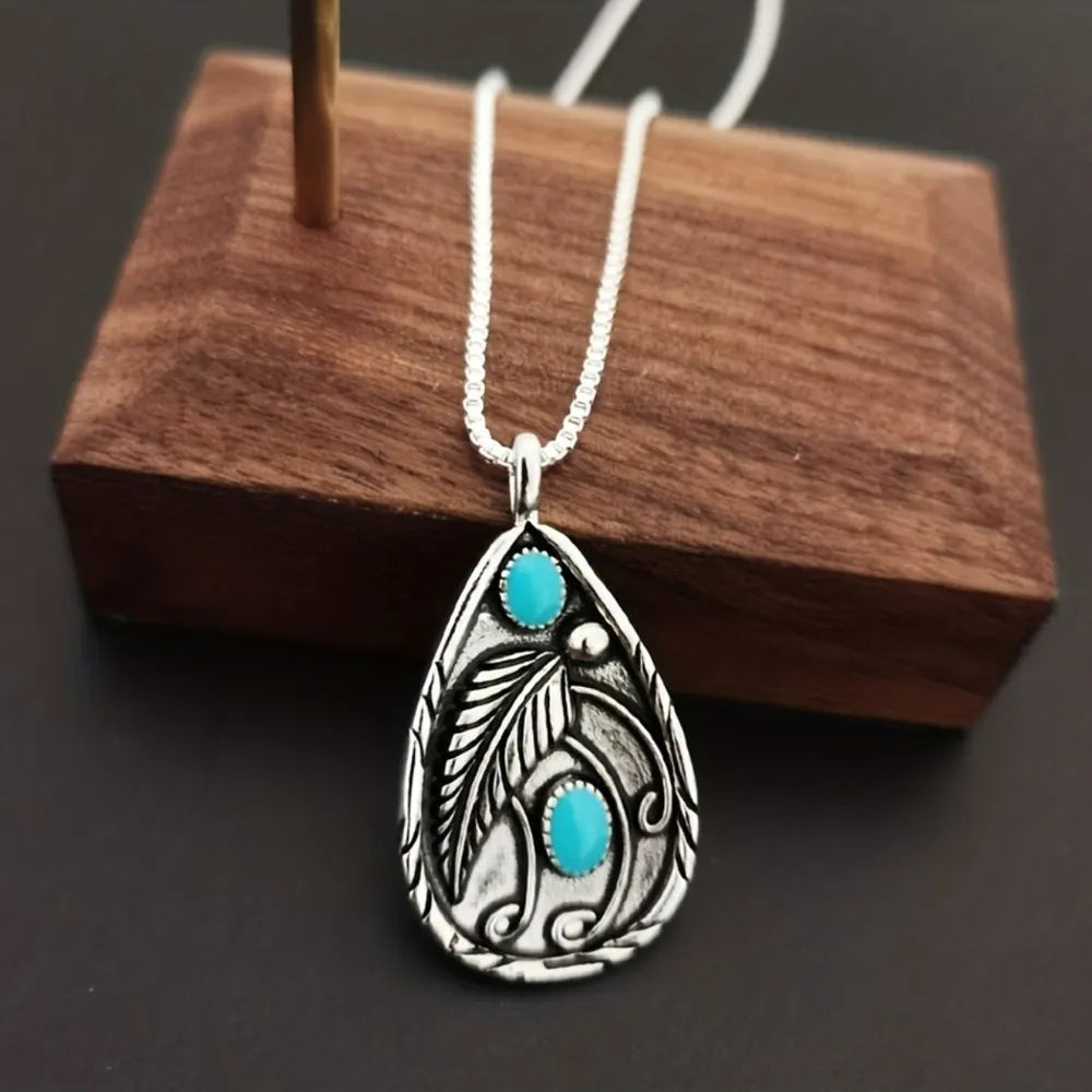 Silver pendant with turquoise stones and feather detail on a chain